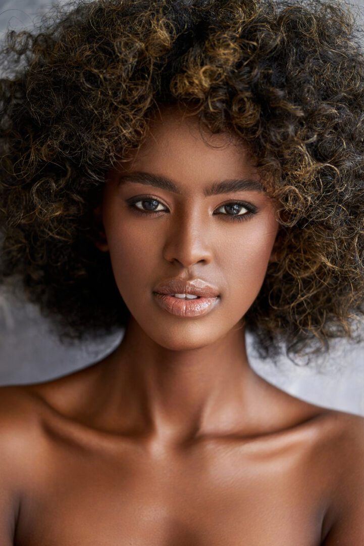 Crop young ethnic female with curly hair looking at camera on blurred background