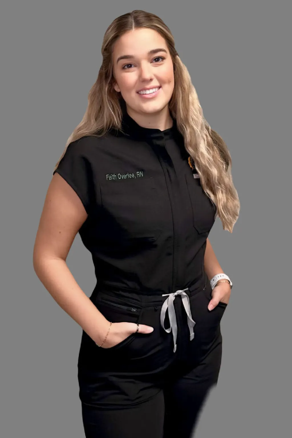 Woman smiling in a casual black jumpsuit with a drawstring waist.