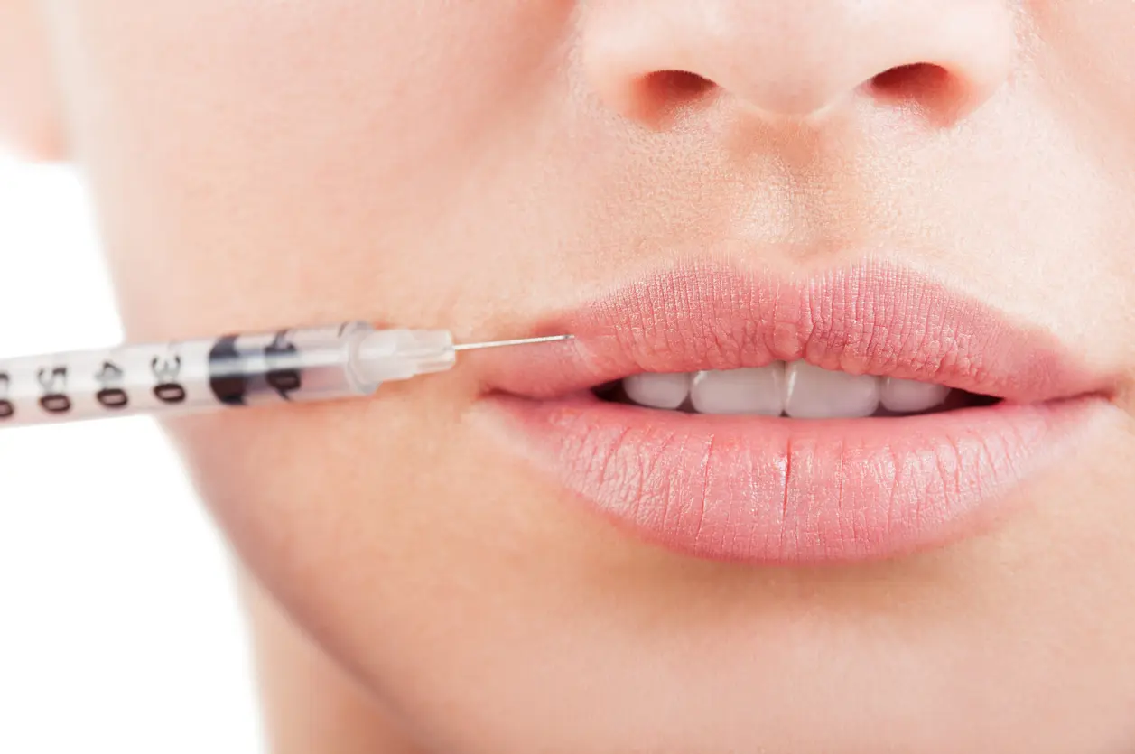 Closeup of beautiful mouth and lips with botox and syringe